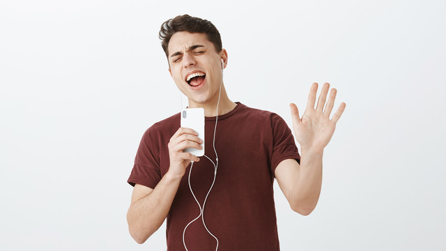 ein Mann mit Kopfhörern singt in sein Handy
