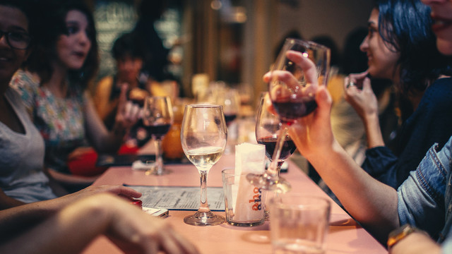 Freundinnen die an einem Tisch sitzen und Wein trinken