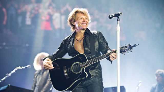 Jon Bon Jovi steht auf der Bühne bei einem Konzert und lacht