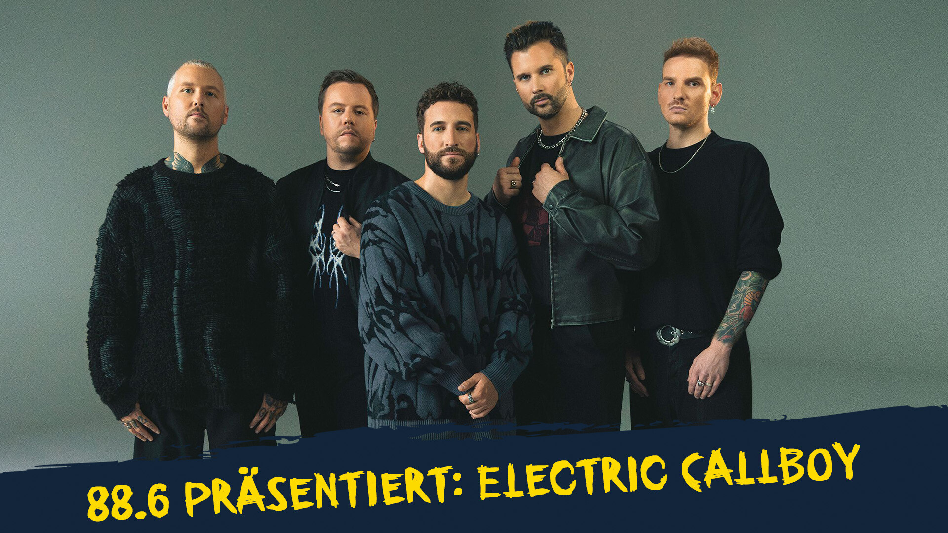 Die Bandmitglieder von Electric Callboy stehen vor einem grauen Hintergrund Die Bandmitglieder von Electric Callboy stehen vor einem grauen Hintergrund