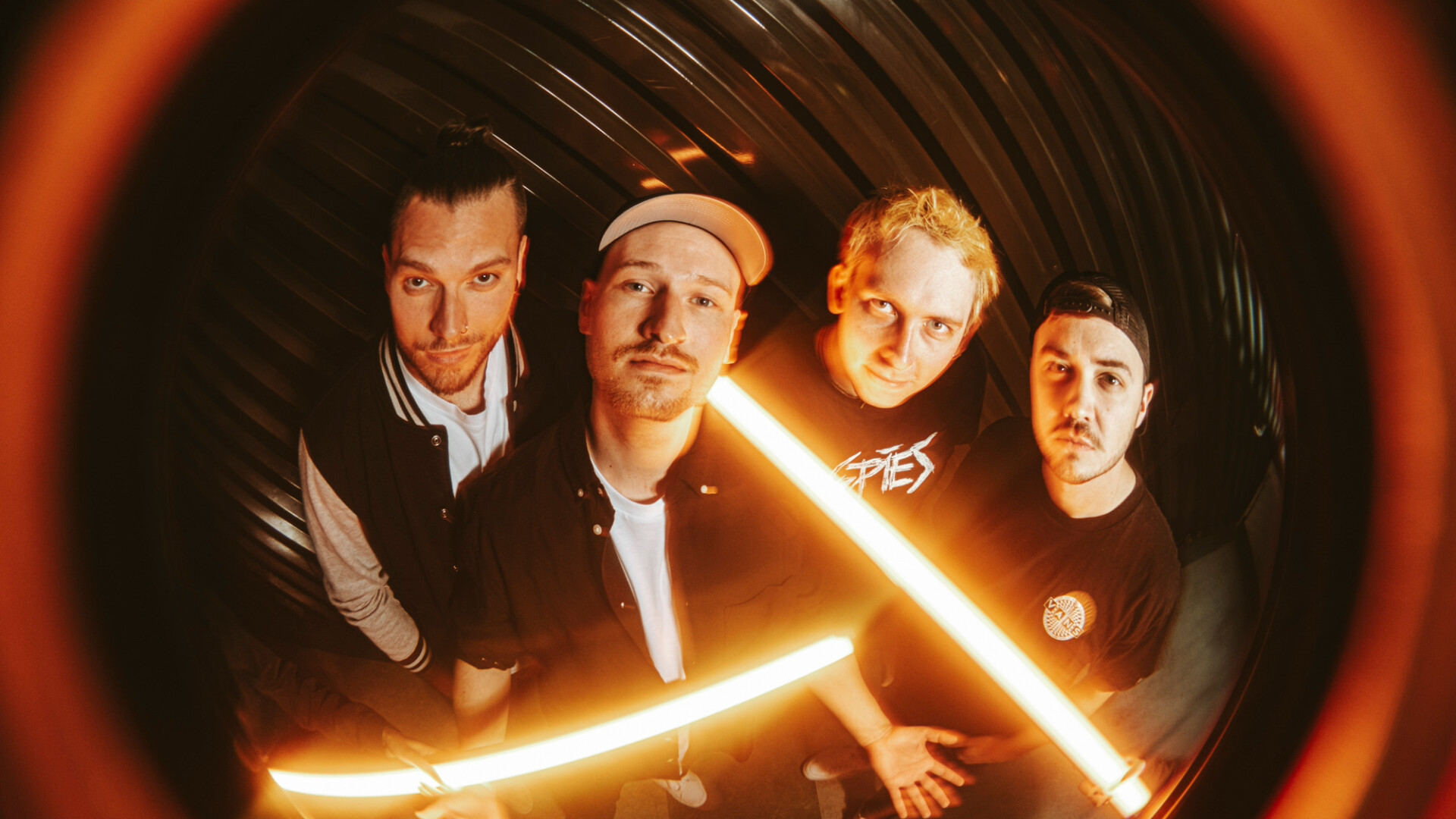 Die Attic stehen vor schwarzer wand mit orangem Neon beleuchtet