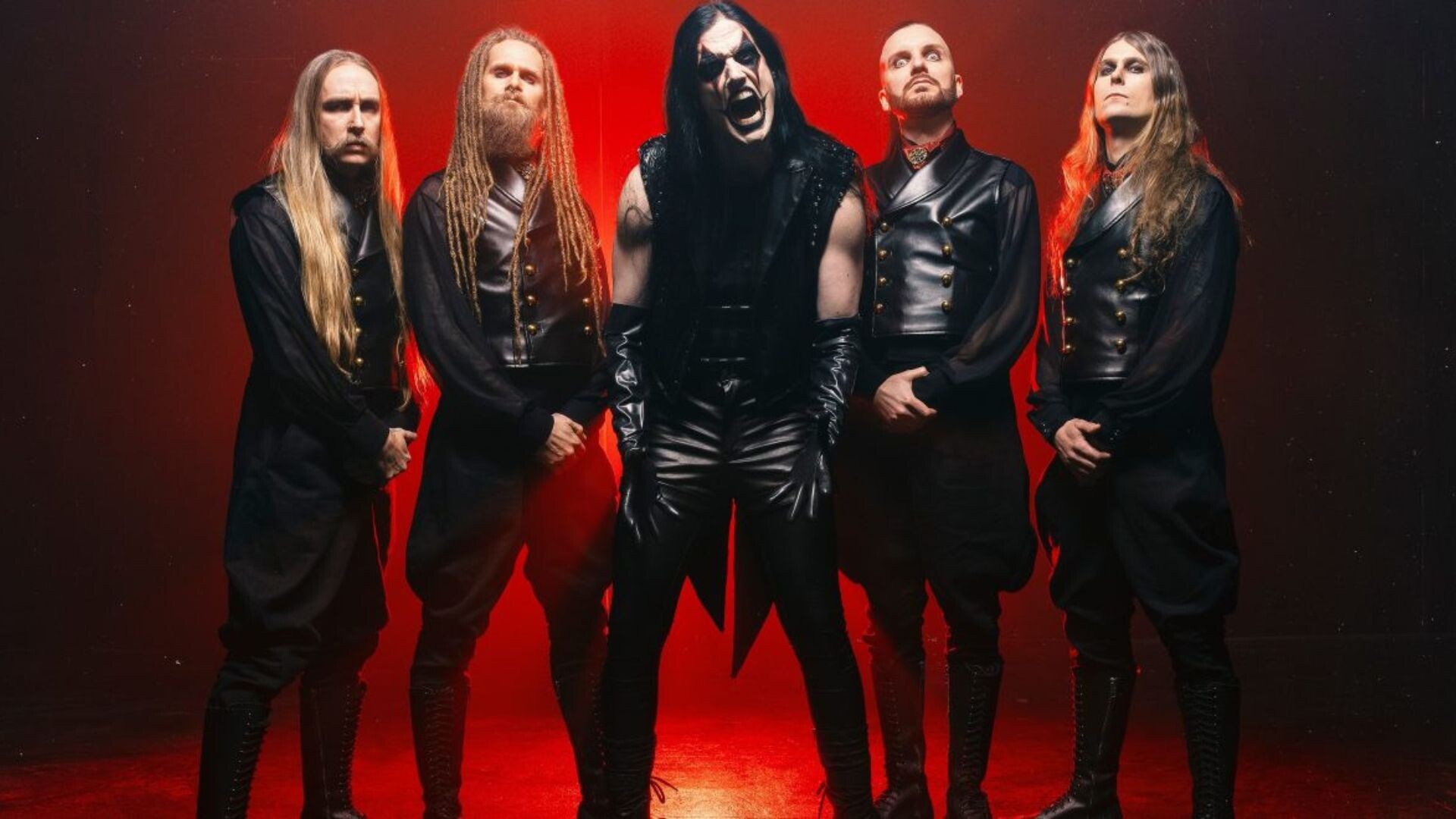 Die Band steht vor einem Rot beleuchteten Hintergrund