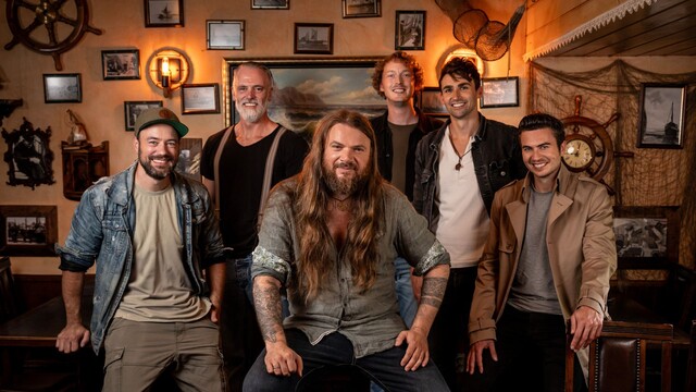Bandfoto von Versengold mit allen sechs Mitgliedern, sie stehen in einer maritim und rustikal eingerichteten bar