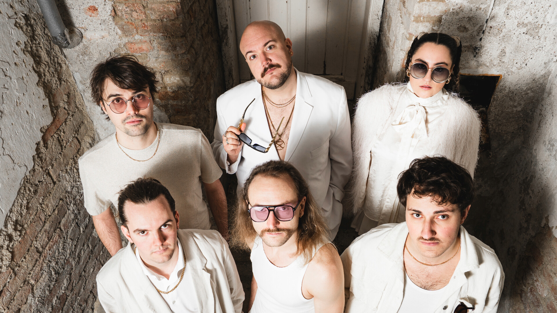Die Band Sankt Krinzinger posiert in weißer feiner Kleidung in eine maroden Keller