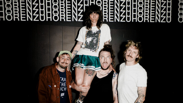 Die Band Baits trägt ihre Sängerin vor schwarzem Hintergrund auf den Schultern