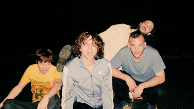 Die Band posiert lustig vor schwarzem Hintergrund