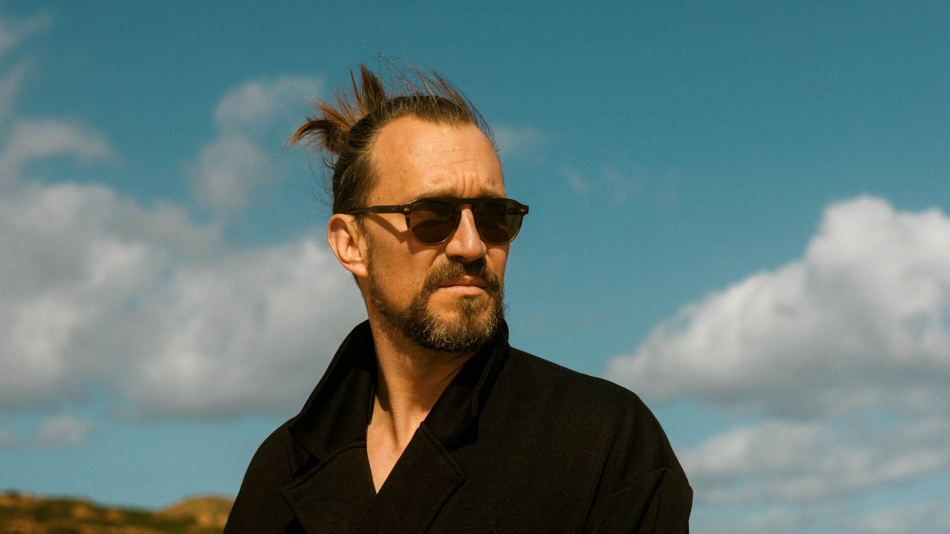 Evon Rose steht mit Sonnenbrille am Strand