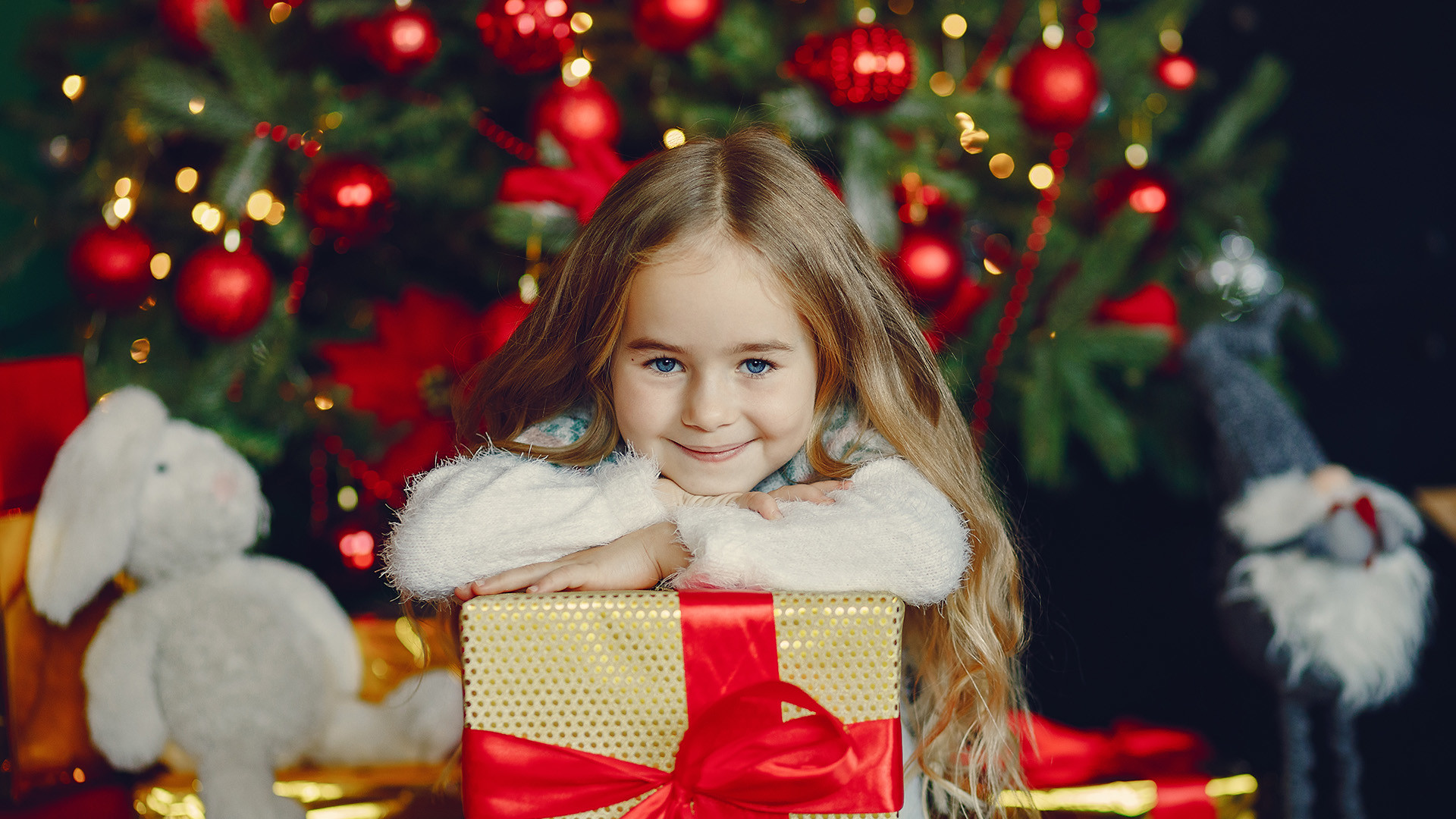 Mädchen mit Geschenk vorm Christbaum