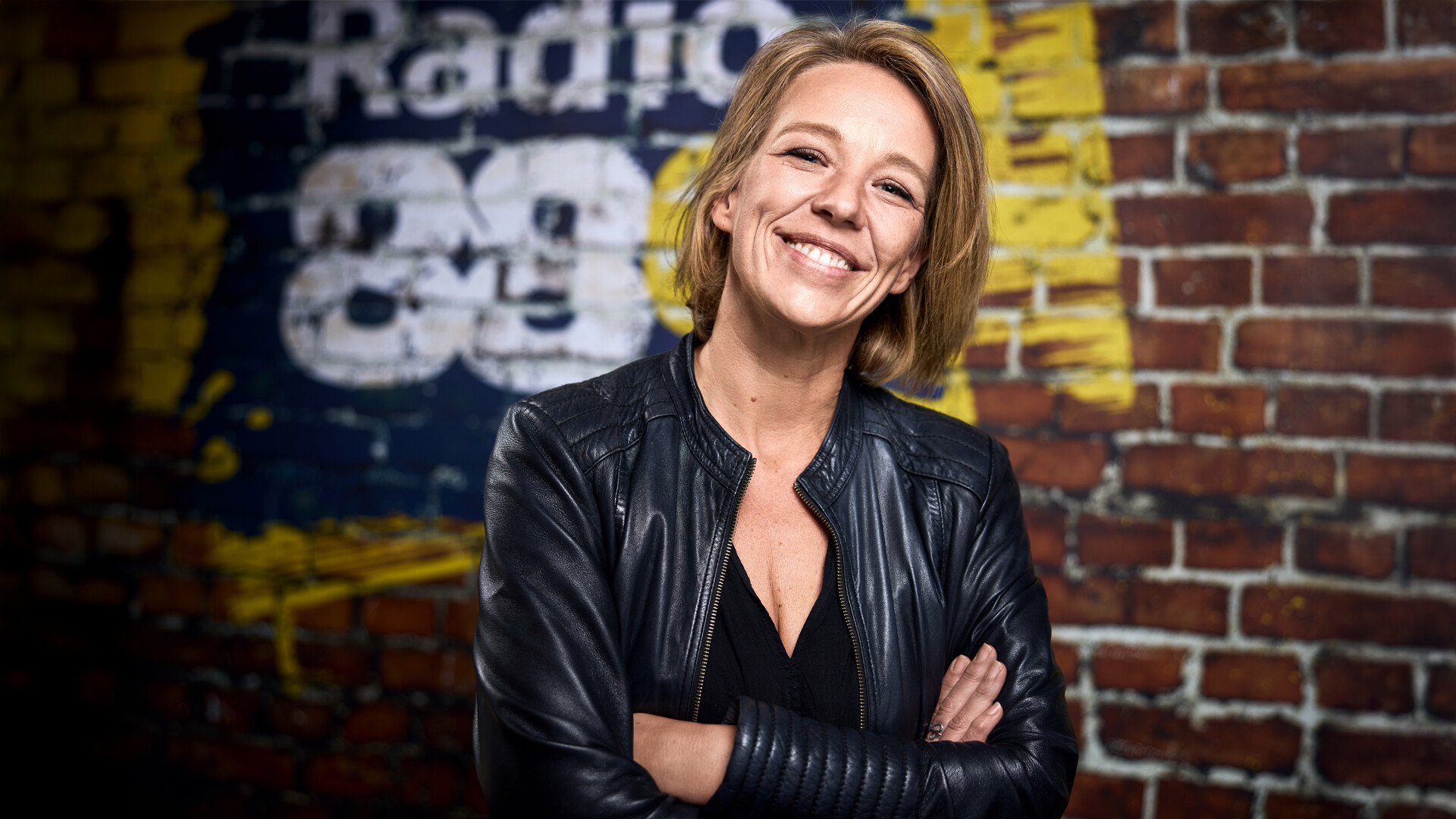 Moderatorin Irene Pravits vor einer Ziegelwand mit Radio 88.6 Logo