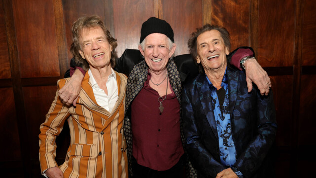 Mick Jagger, Keith Richards und Ron Wood vor einer dunklen Holzwand