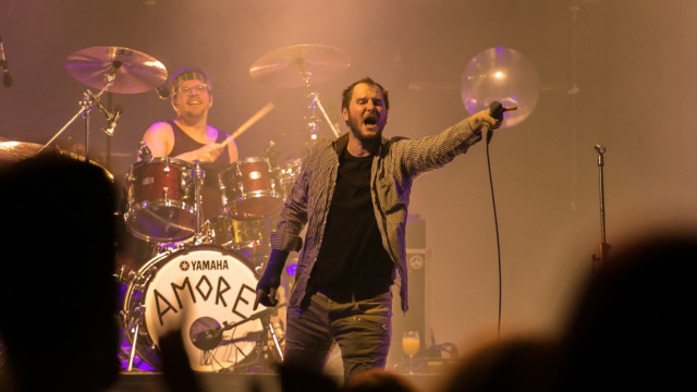 Marco Michael Wanda steht bei Konzert auf der Bühne und hält das Mikrofon ins Publikum