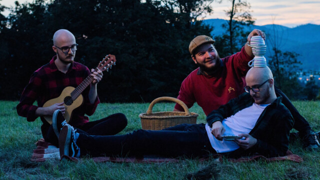 Die Band posiert bei einem Picnic mit Gitarre