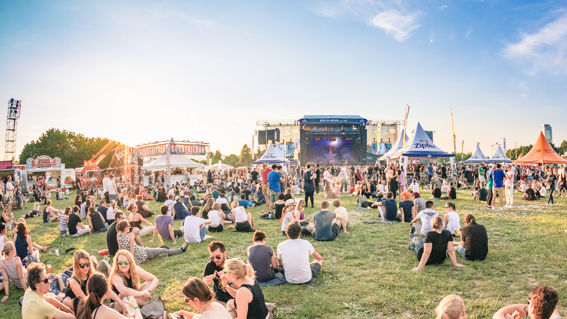 Festivalsommer Auf einer Wiese sitzen Menschen bei blauem Himmel