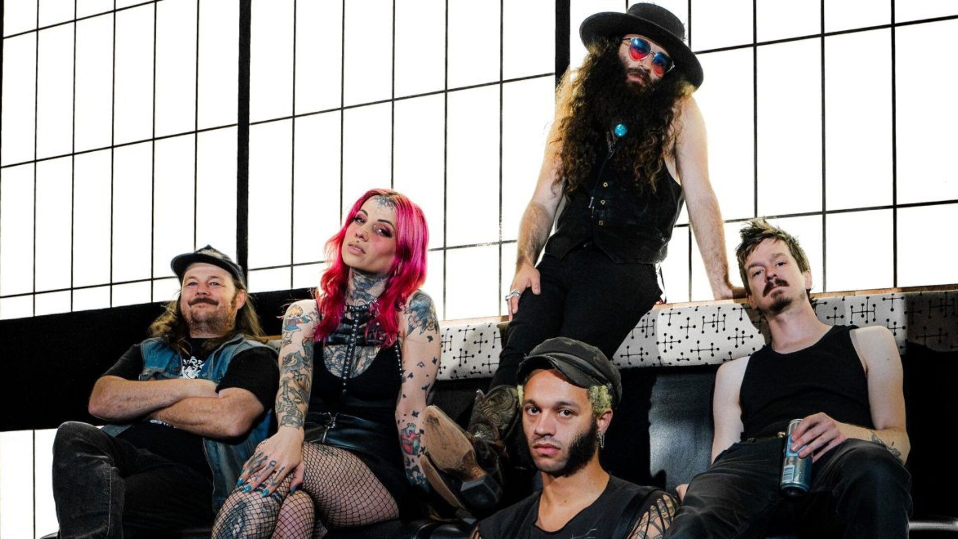 Die Band sitzt vor einem großen, Hellen Fenster im Industrial Look