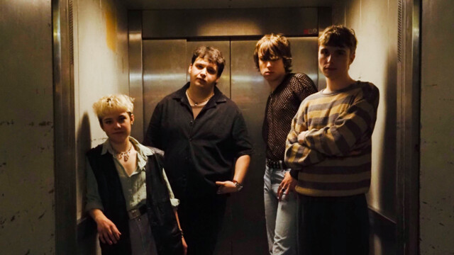 Die Band posiert zu viert in einem Aufzug