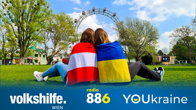 Zwei Frauen mit der der Österreich und der Ukraine Flagge sitzen vorm Riesenrad auf der Kaiserwiese